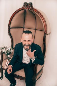 close up. cheerful groom sitting in a stylish chair .people and events