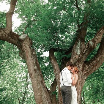 happy newlyweds standing near a large spreading tree. romantic moment