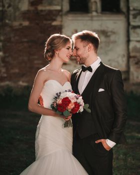 in full growth.the bride with a wedding bouquet and the groom standing near the old manor.