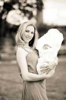 photo in retro style.a young mom with a newborn baby outdoors