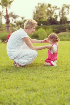 Young Mother and cute little daughter enjoying free time playing outside at backyard on the grass, happy family in nature concept