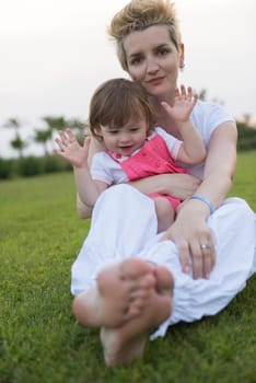 Young Mother and cute little daughter enjoying free time playing outside at backyard on the grass, happy family in nature concept