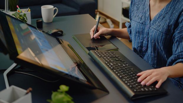 Close up of photography studio equipment and technology on desk. Hands of artist using retouching software on touch screen monitor and graphic tablet and stylus. Woman editing pictures