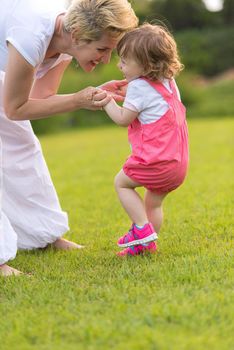 Young Mother and cute little daughter enjoying free time playing outside at backyard on the grass, happy family in nature concept