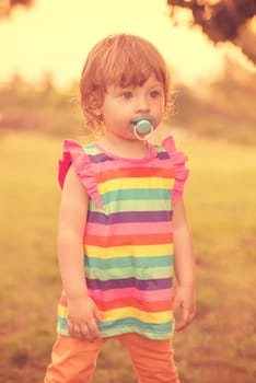 playful cute little girl cheerfully spending time while running in the spacious backyard on the grass