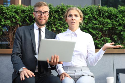 Business people shocked by information from laptop