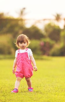 playful cute little girl cheerfully spending time while running in the spacious backyard on the grass