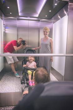 young father taking pictures of his happy family in the mirror of the elevator