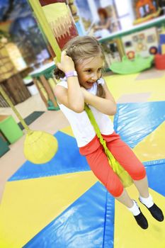 cheerful little girl climbing the rope in the entertainment center