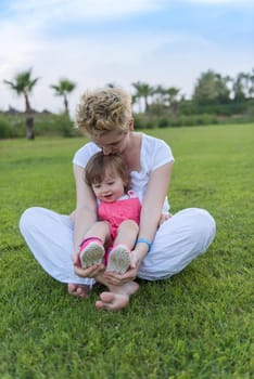 Young Mother and cute little daughter enjoying free time playing outside at backyard on the grass, happy family in nature concept