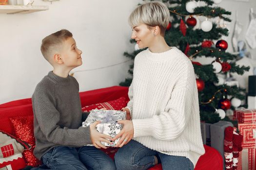 Beautiful mother in a white sweater. Family in a christmas decorations. Little boy in a room