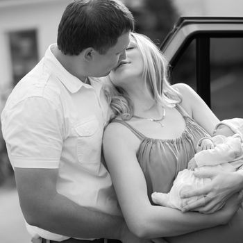 photo in retro style. happy husband kissing his wife with a newborn baby