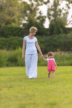 Young Mother and cute little daughter enjoying free time playing outside at backyard on the grass, happy family in nature concept