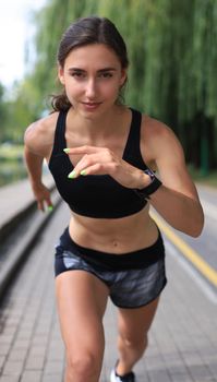Young woman in sports clothing running while exercising outdoors