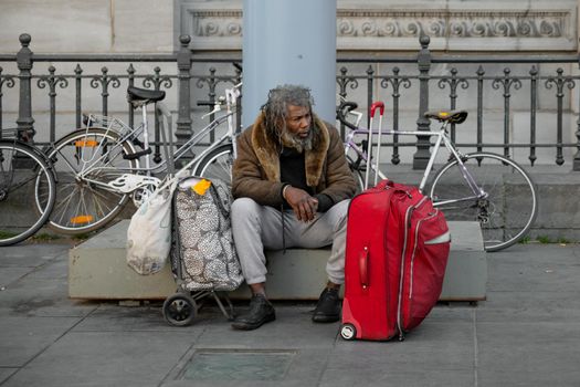 ANTWERP , BELGIUM - APRIL 20, 2019: Homeless unhappy drunk man with suitcases on the street