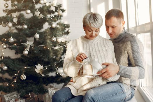 Family at home. Couple near christmas decorations. Woman in a gray sweater.