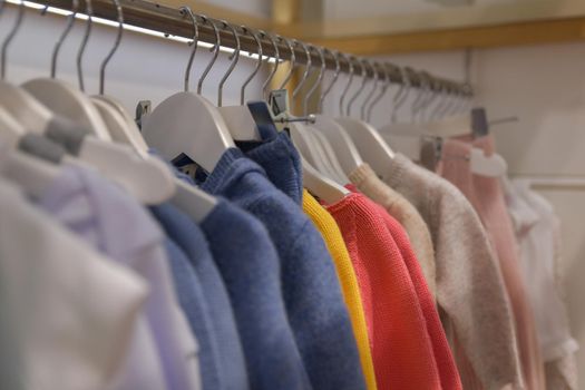 Blouses and sweaters hang on a hanger in the store Row