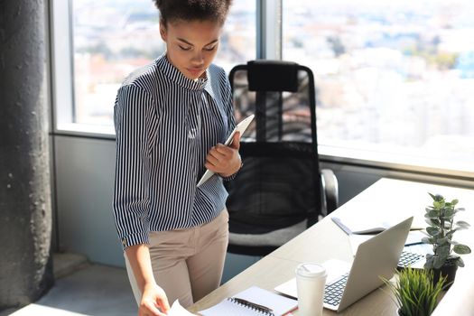 Beautiful african american business woman in smart casual wear working on laptop in the office