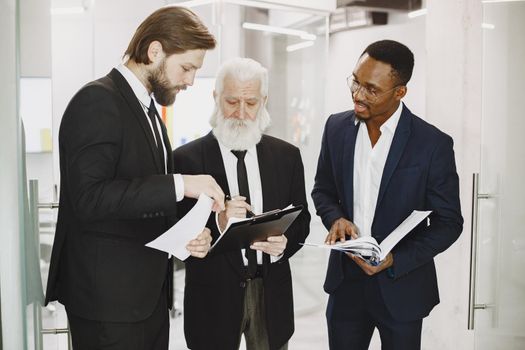 African man in a black suit. International partners. Young guys with senior man.