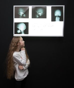 attentive detective girl looking at the Board with physical evidence. the concept of a hobby