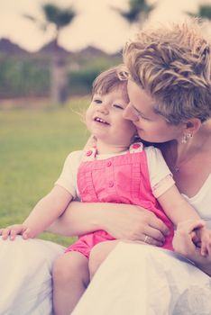 Young Mother and cute little daughter enjoying free time playing outside at backyard on the grass, happy family in nature concept