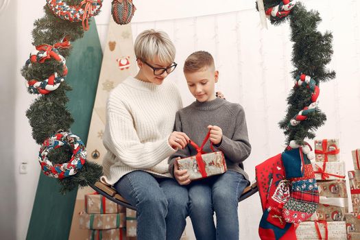 Beautiful mother in a white sweater. Family in a christmas decorations. Little boy in a room