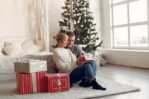 Family at home. Couple near christmas decorations. Woman in a gray sweater.