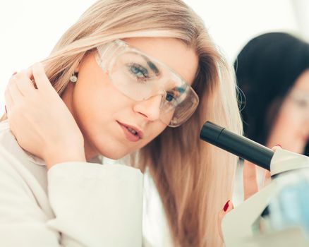 close up.a modern female scientist looks into a microscope in a laboratory. science and health