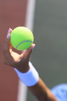 Woman holding a tennis ball with tennis court in the background