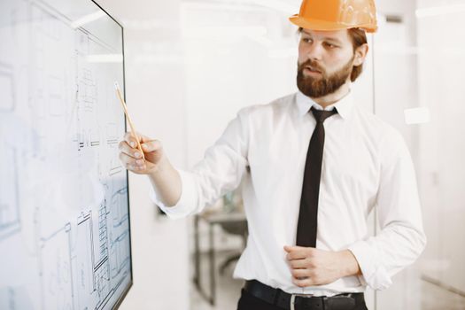 Architect and engineer. Man shows plan of building. TV screen.