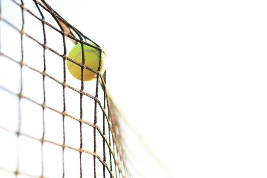 Bright greenish yellow tennis ball hitting the net