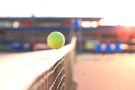 Bright greenish yellow tennis ball hitting the net