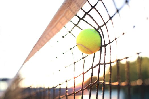 Bright greenish yellow tennis ball hitting the net