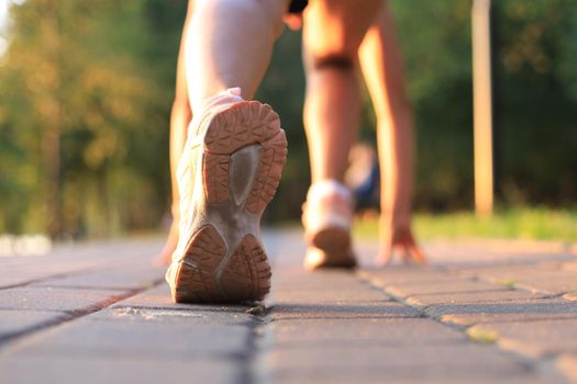 Runner feet running on road closeup on shoe, outdoor at sunset or sunrise