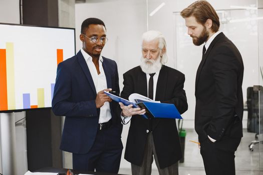 African man in a black suit. International partners. Young guys with senior man.