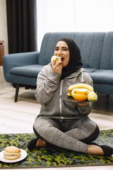 Woman choosing between fruits and burger.