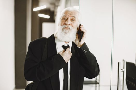 Elegant man at the office. Senior with a mobile phone.