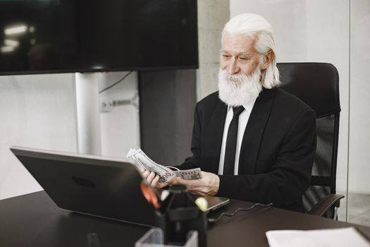 Old-fashioned man sitting at the table. Elegant man at the office. Senior with a money.