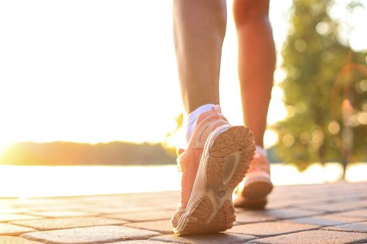 Runner feet running on road closeup on shoe, outdoor at sunset or sunrise