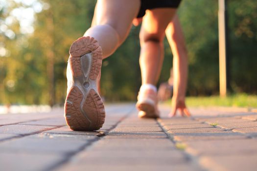 Runner feet running on road closeup on shoe, outdoor at sunset or sunrise