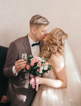 close up. bride and groom with glasses of champagne kissing each other. holidays and events.