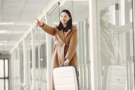 Woman at the airport. Girl with suitcase. Lady in a brown coat.