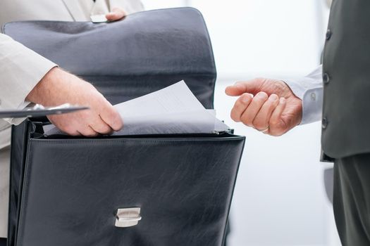 close up. businessman taking out of his briefcase business documents. business concept