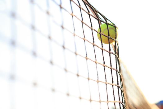 Bright greenish yellow tennis ball hitting the net