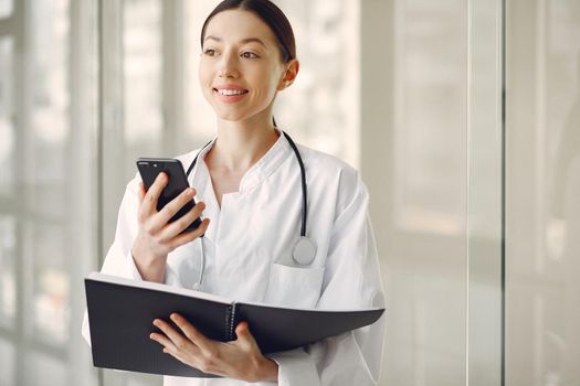 Woman in a uniform. Doctio with a stethoscope. Brunette in a hall.