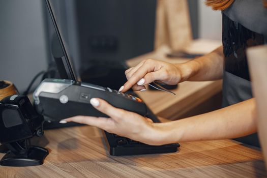 Womanl pays for the purchase. Credit card in hand. Lady uses the terminal.