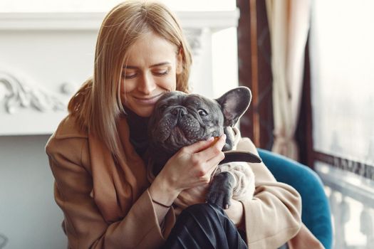 Woman with dog. Lady in a brown coat. Girl play with bulldog. Woman in a cafe.