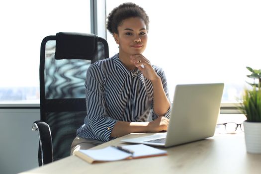 Portrait of beautiful young african american woman working with laptop while sitting at the table