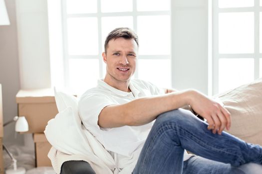 close up. happy man sitting on the couch in his new apartment