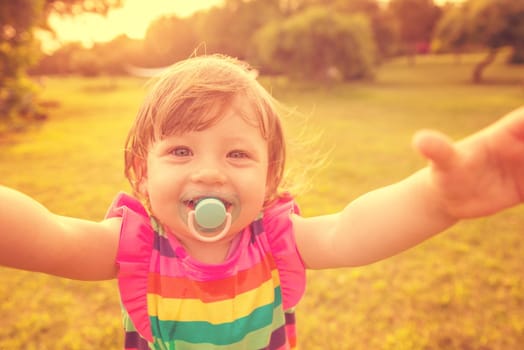 playful cute little girl cheerfully spending time while running in the spacious backyard on the grass